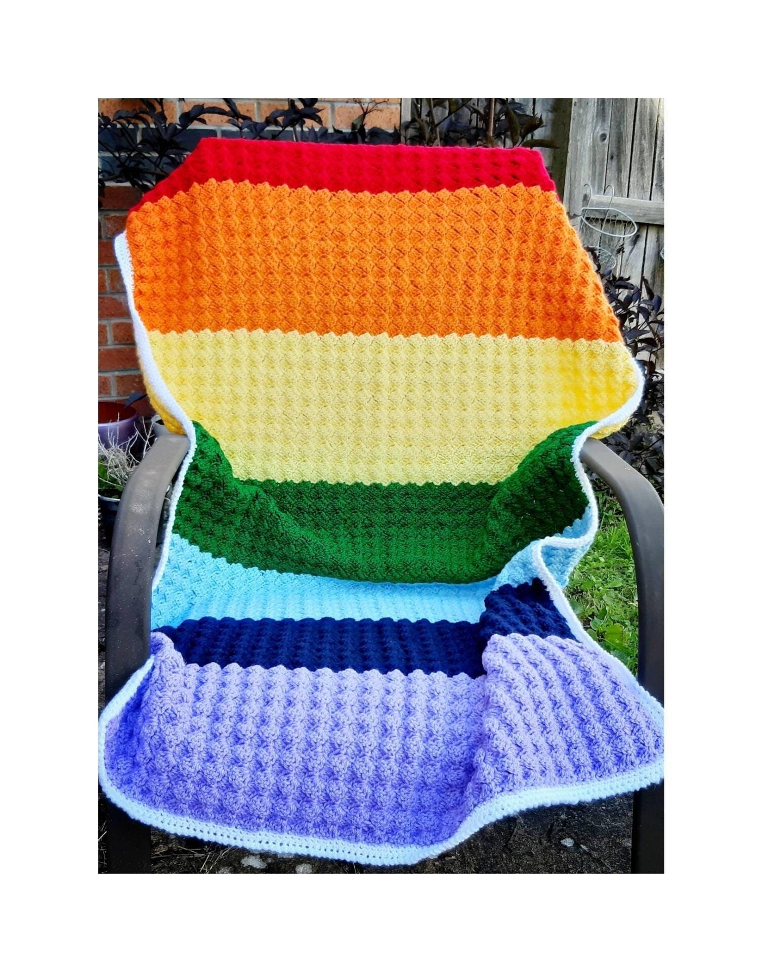 Handmade rainbow crochet blanket, striped with white edging. Shown in chair to illustrate sizing.Chakra colours