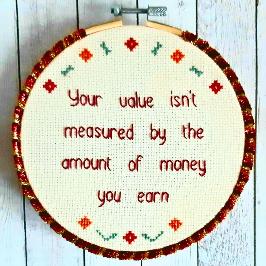 Your value isn't measured by the amount of money you earn, completed cross stitch quote - Thistleflat Crafts