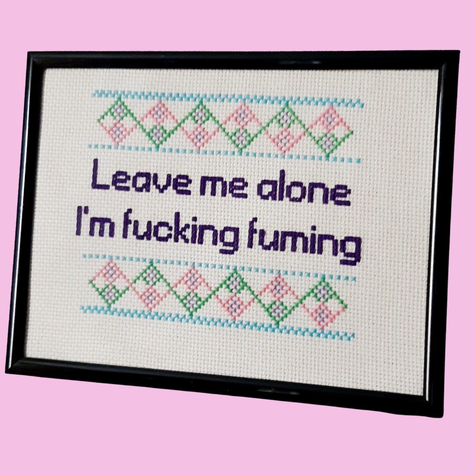Completed cross stitch quote 'leave me alone I'm fucking fuming' mounted in narrow black frame
